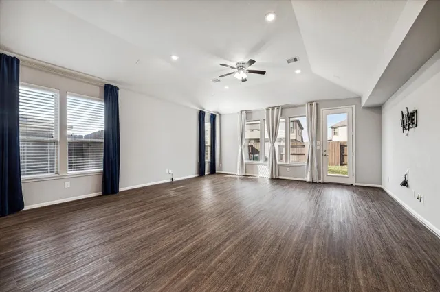a view of an empty room with kitchen and window
