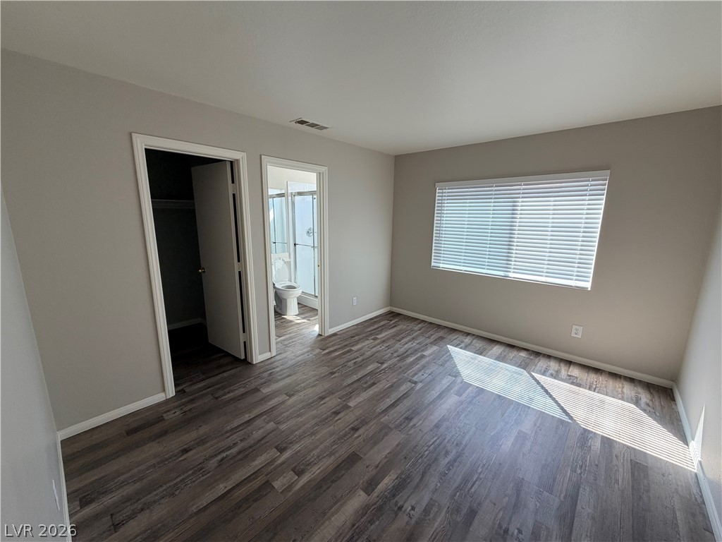Rich wood-inspired floors and a wide window create a comfortable primary bedroom retreat.