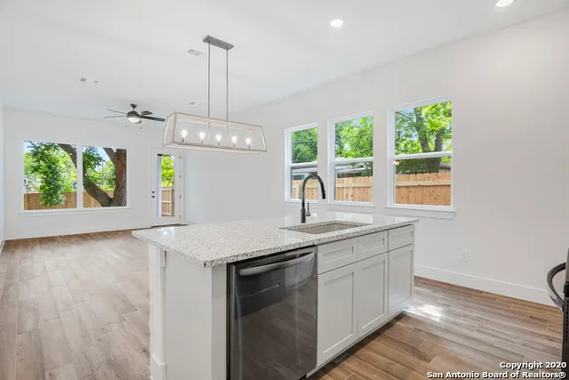 a view of a kitchen with granite countertop wooden floor stainless steel appliances and a chandelier