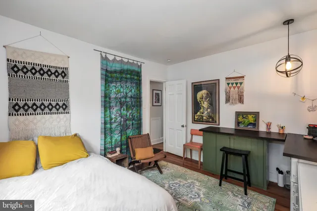 a bedroom with a bed a desk and chair with a mirror