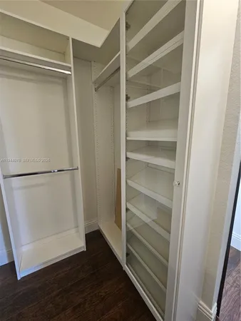 an empty room with wooden floor closet and windows