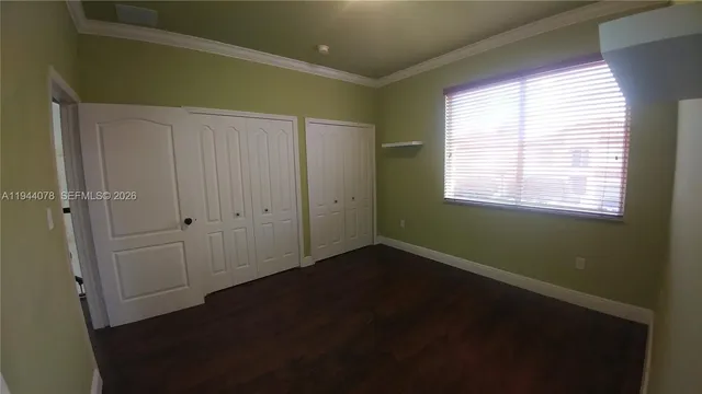 a view of an empty room with wooden floor and windows