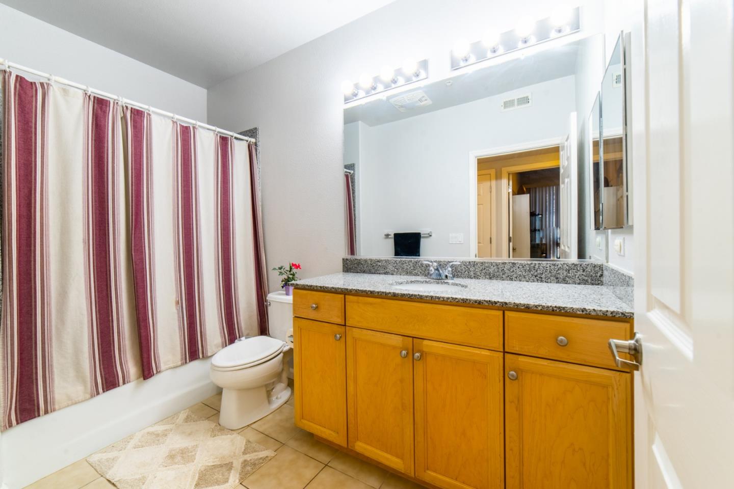 88 North Jackson Avenue, Unit 127 San Jose, CA 95116 - Photo 7 of 10 a bathroom with a granite countertop sink and a mirror