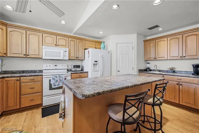 a kitchen with stainless steel appliances granite countertop a table chairs sink refrigerator and cabinets