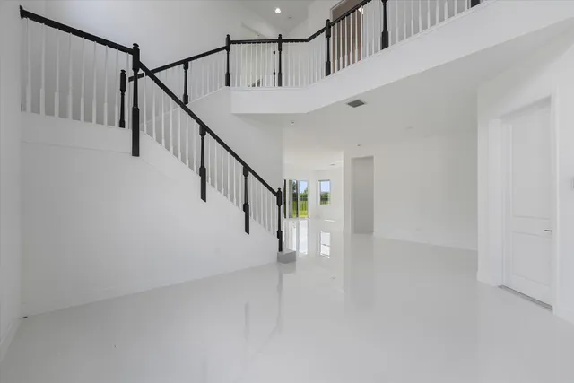 a view of an empty room with a floor to ceiling window and kitchen view
