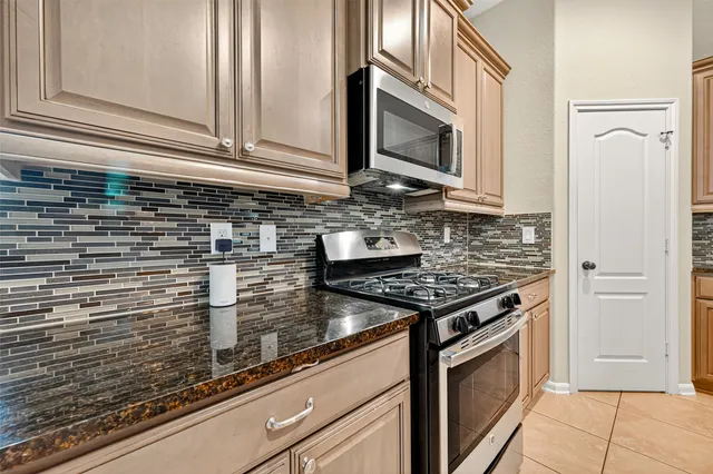a kitchen with granite countertop a stove top oven microwave and cabinets