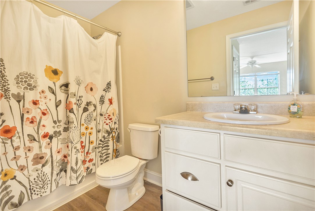 726 Lookover Drive Anderson, SC 29621 - Photo 29 of 32 This bright bathroom features a single vanity, a toilet, and a shower with a decorative curtain.
