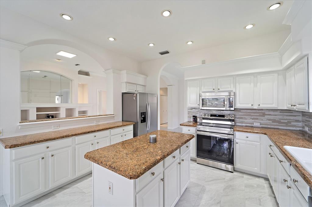 6585 Waters Edge Way Lakewood Ranch, FL 34202 - Photo 12 of 59 a kitchen with stainless steel appliances granite countertop a sink stove and refrigerator
