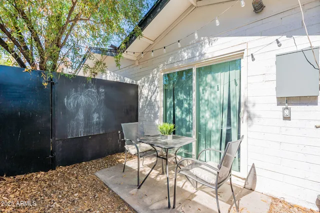 a patio with table and chairs and potted plants