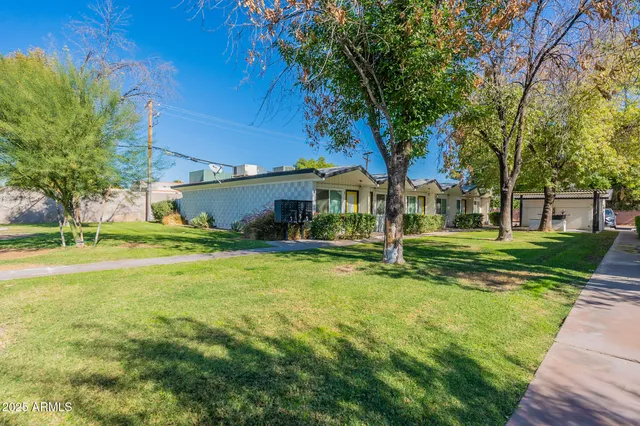a view of a white house in a big yard with palm trees