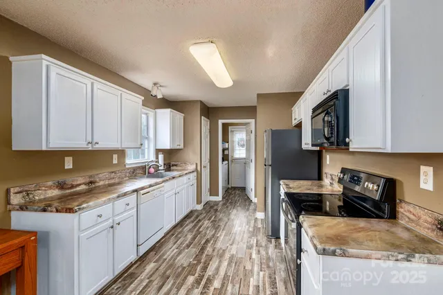 a kitchen with granite countertop a stove top oven a sink dishwasher and a refrigerator with wooden floor