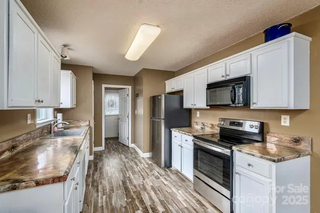 a kitchen with granite countertop a sink stainless steel appliances and white cabinets