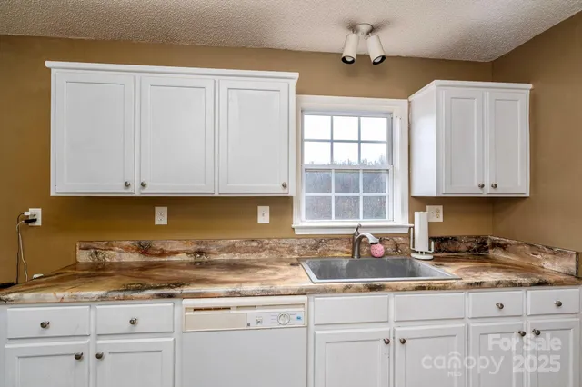 a kitchen with granite countertop white cabinets and a sink