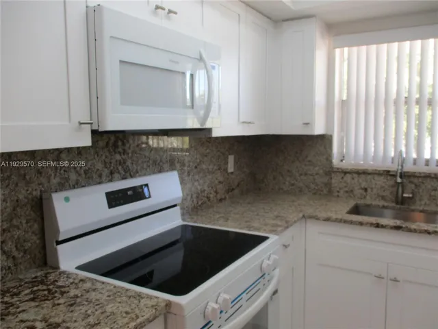 a kitchen with granite countertop a sink window and cabinets