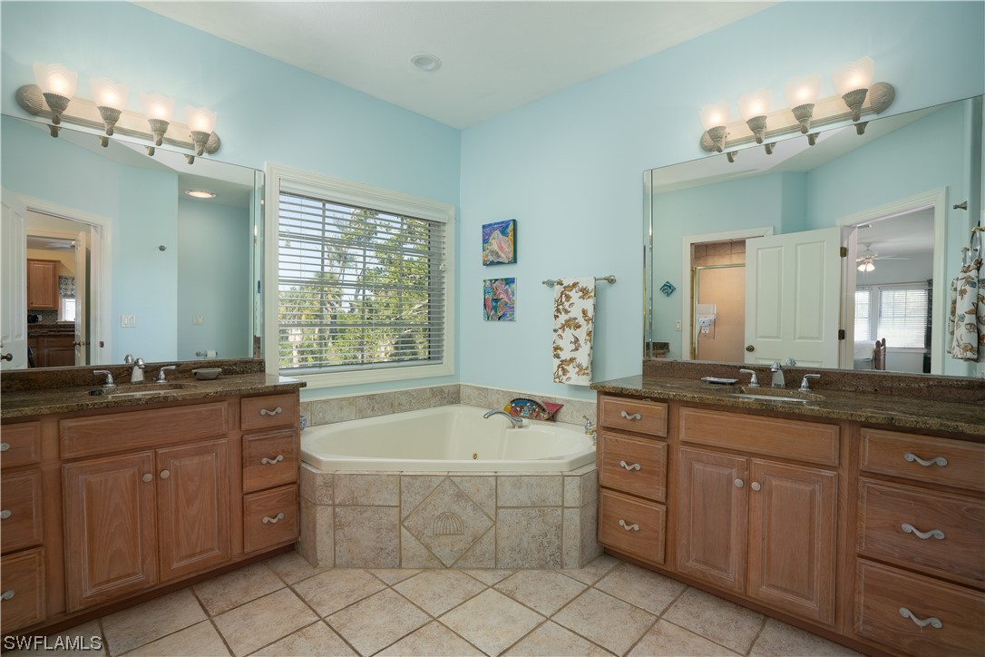 2130 Sunset Circle Sanibel, FL 33957 - Photo 19 of 36 a spacious bathroom with a granite countertop double vanity sink a mirror a bathtub and window