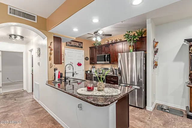 a kitchen with kitchen island granite countertop a sink and refrigerator