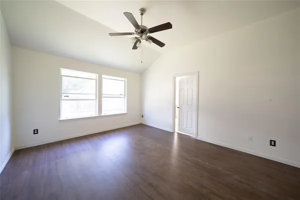 an empty room with wooden floor chandelier fan and windows