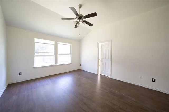 an empty room with wooden floor chandelier fan and windows