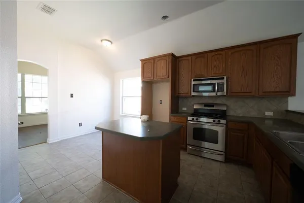 a kitchen with kitchen island granite countertop stainless steel appliances stove microwave and sink