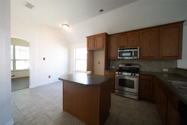 a kitchen with kitchen island granite countertop stainless steel appliances stove microwave and sink
