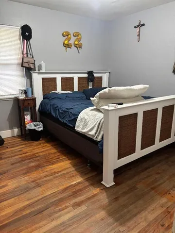 a living room with a bed and wooden floor