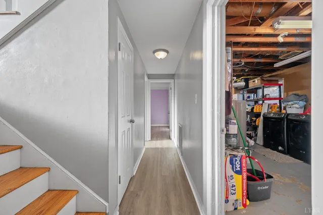 a view of a hallway with wooden floor and a bathroom