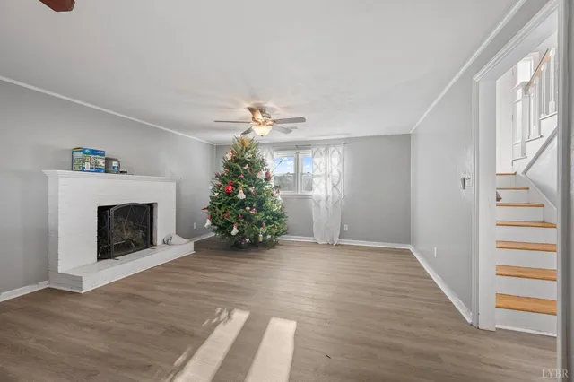 a view of an empty room with wooden floor fireplace and a window
