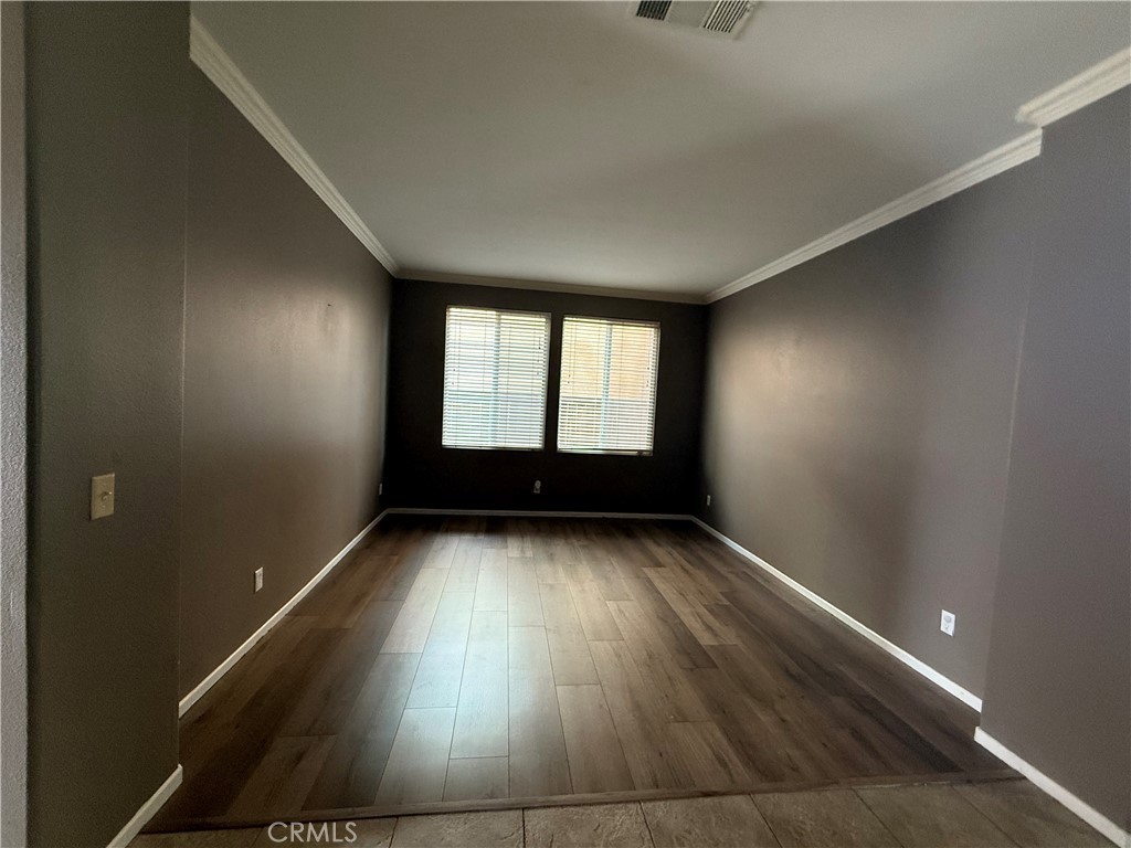 1264 Reisling Drive Perris, CA 92571 - Photo 13 of 15 an empty room with wooden floor and windows