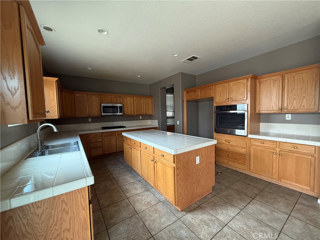 1264 Reisling Drive Perris, CA 92571 - Photo 3 of 15 a kitchen with stainless steel appliances granite countertop wooden cabinets a sink a stove a refrigerator and island