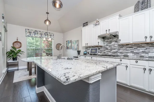 a kitchen with stainless steel appliances granite countertop a sink a stove and a wooden floors
