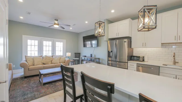 a kitchen with stainless steel appliances granite countertop a refrigerator a oven a sink a dining table and chairs with wooden floor