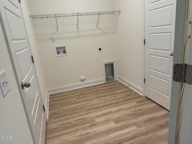 an empty room with wooden floor cabinet and windows