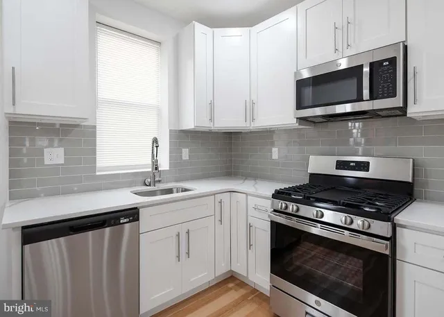 a kitchen with stainless steel appliances granite countertop white cabinets a sink and a stove