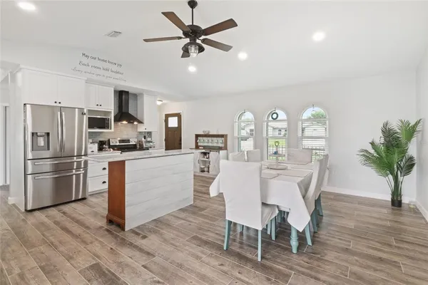 a kitchen with stainless steel appliances a dining table chairs refrigerator and sink