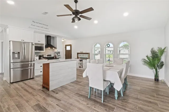 a kitchen with stainless steel appliances a dining table chairs refrigerator and sink