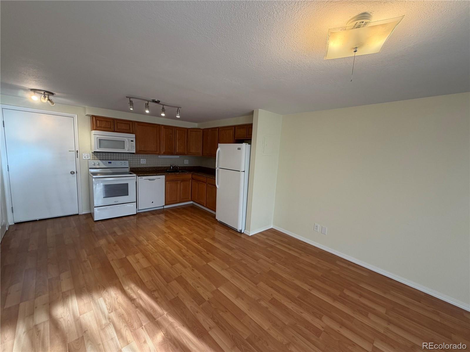 1304 South Parker Road, Unit 258 Denver, CO 80231 - Photo 2 of 9 a kitchen with a wooden floor and a stove top oven