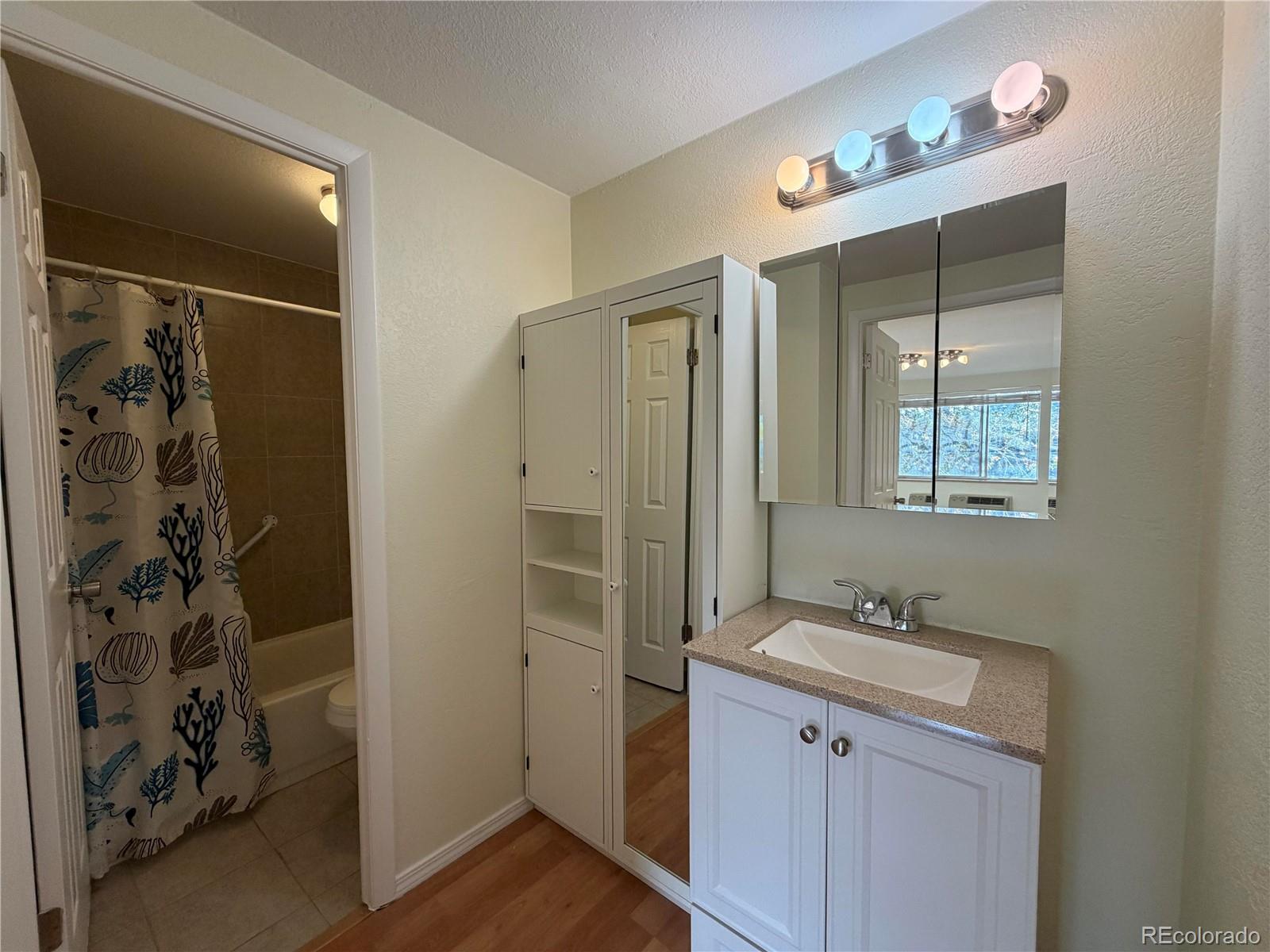 1304 South Parker Road, Unit 258 Denver, CO 80231 - Photo 5 of 9 a bathroom with a double vanity sink a mirror and shower