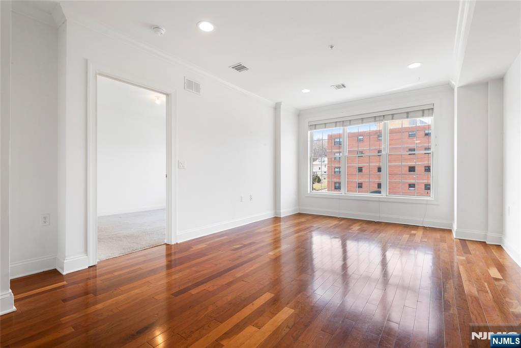 54 Polifly Road, Unit 311 Hackensack, NJ 07601 - Photo 5 of 20 a view of an empty room with wooden floor and a window