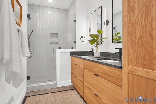 a bathroom with a granite countertop shower a sink and a mirror