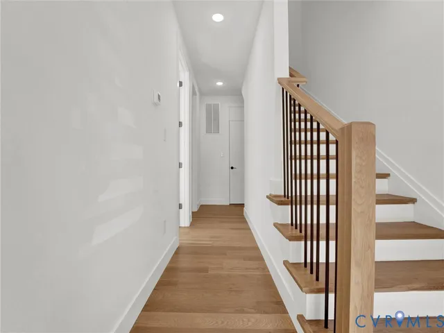 a view of a hallway with wooden floor and staircase