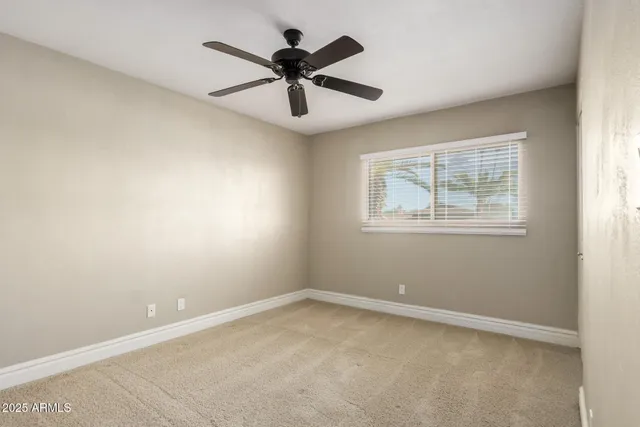 an empty room with a window and a fan