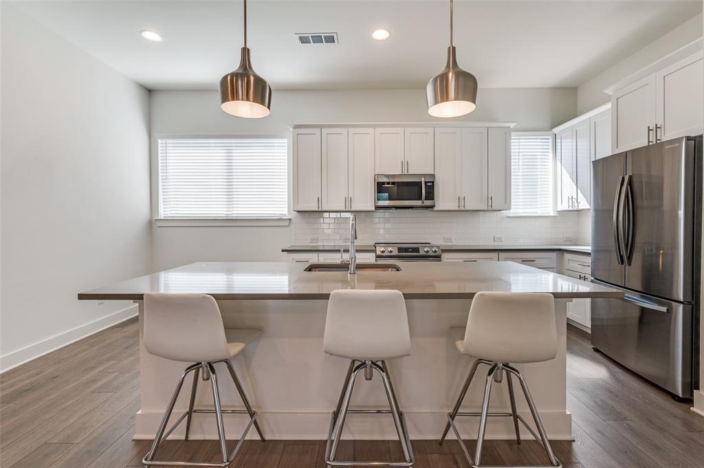 a kitchen with stainless steel appliances a dining table chairs refrigerator and microwave