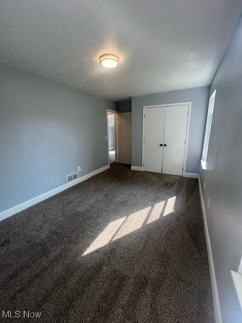 Unfurnished bedroom featuring a closet, carpet, and a textured ceiling