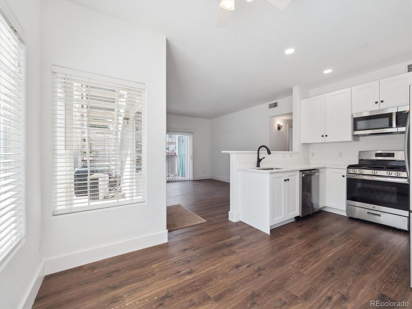 3855 East Canyon Ranch Road, Unit 104 Highlands Ranch, CO 80126 - Photo 5 of 18 a kitchen with wooden floors and white appliances