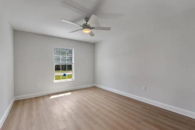 a view of an empty room with a window and wooden floor