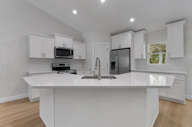a kitchen with stainless steel appliances a refrigerator sink and microwave