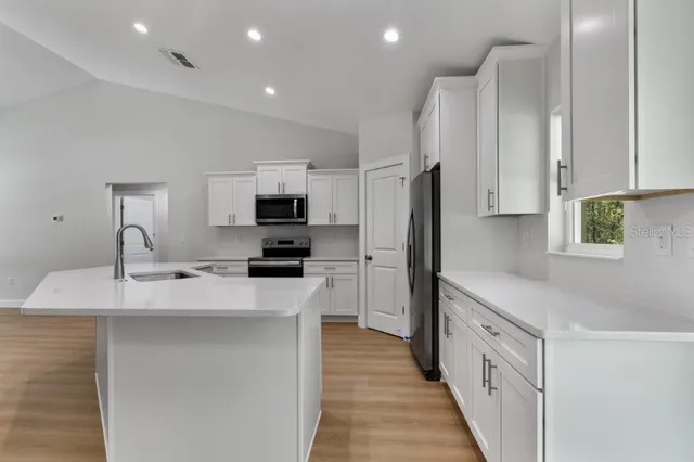 a kitchen with stainless steel appliances a sink stove refrigerator and cabinets