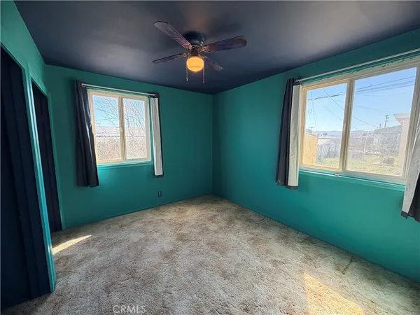 a view of an empty room with a window and a ceiling fan