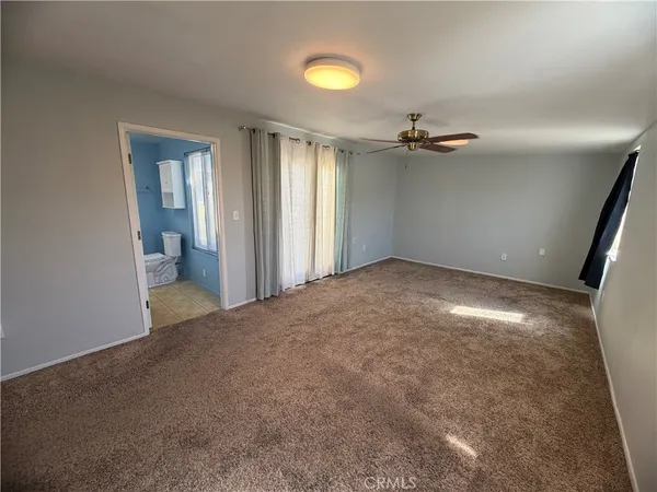 an empty room with a chandelier fan and windows