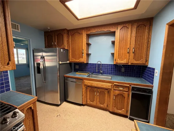 a kitchen with stainless steel appliances granite countertop a refrigerator a sink and wooden cabinets